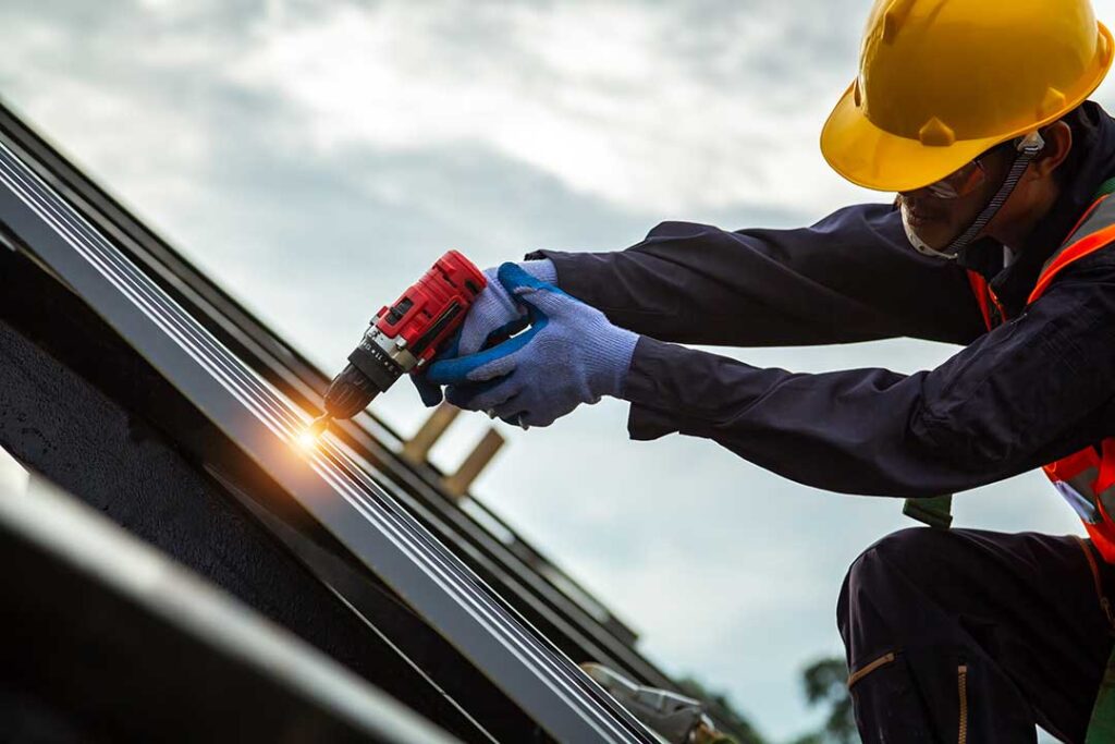 Homeowner inspecting roof shingles and clearing leaves from a gutter beside a two-story house