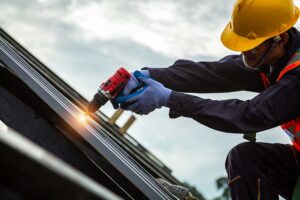 Homeowner inspecting roof shingles and clearing leaves from a gutter beside a two-story house